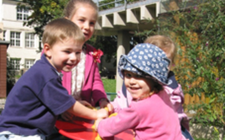 Vier fröhliche Kinder in der Kinderbetreuung der Universität Stuttgart.