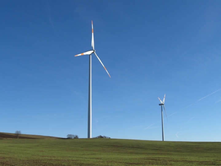 Zwei Windräder vor blauem Himmel.