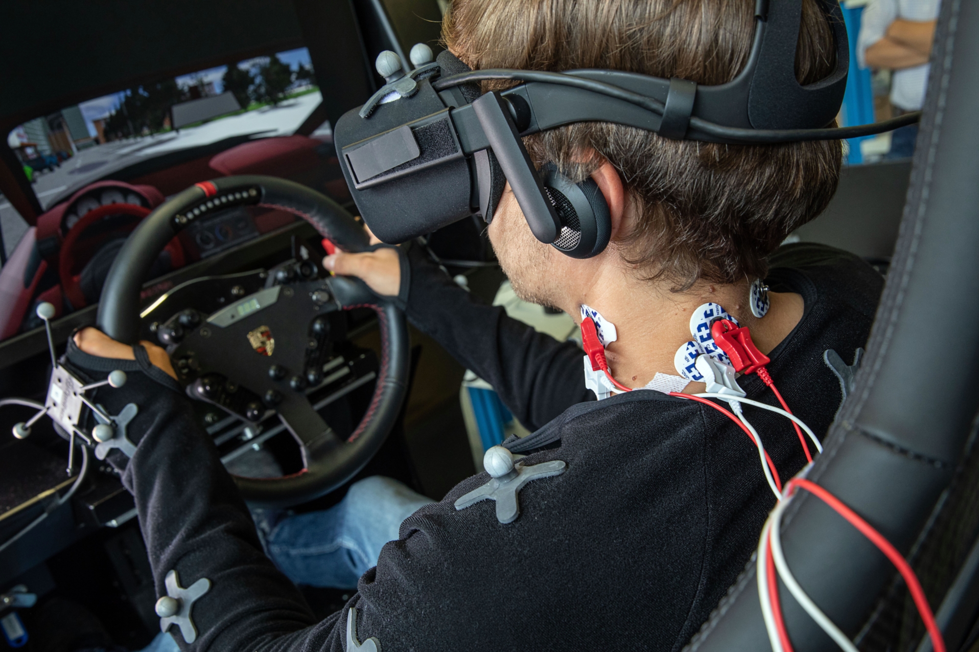 Detailed view of the wires attached to the neck of the man in the driving simulator.