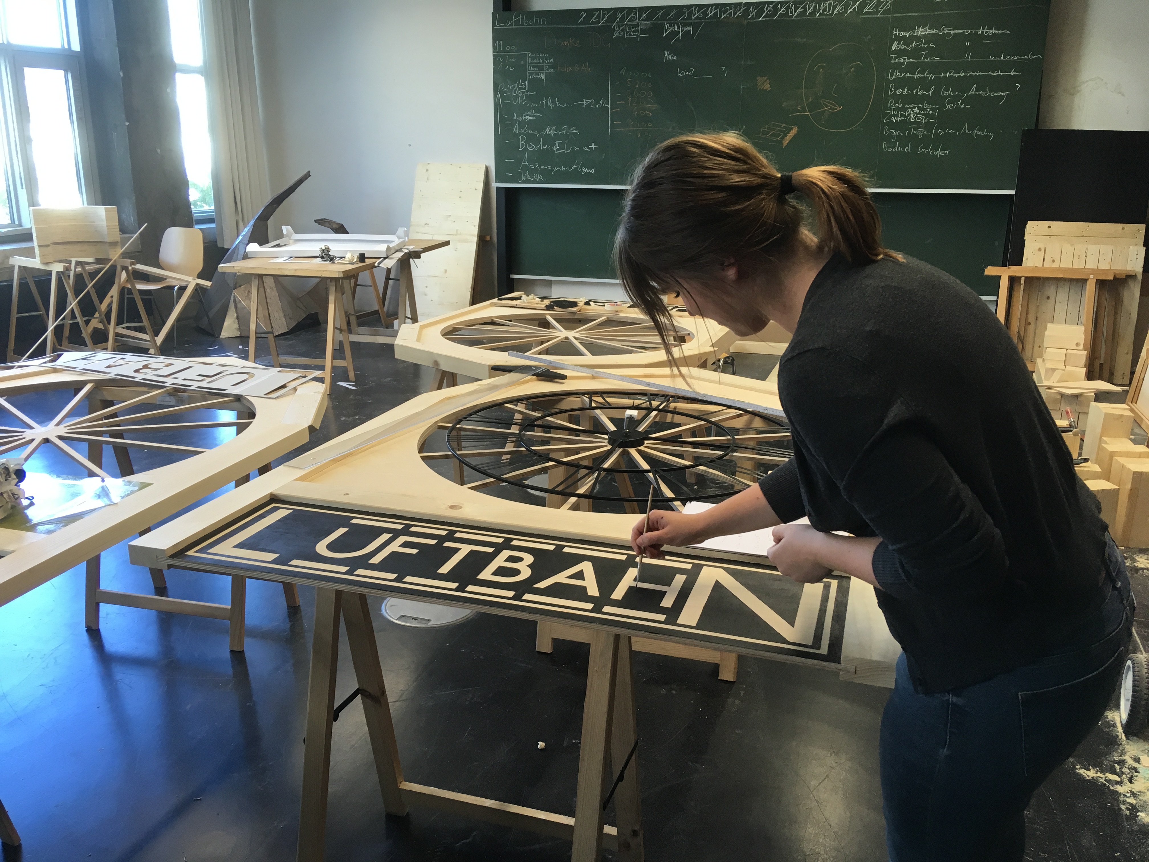 Studentin gestaltet mit einem Pinsel den Schriftzug "Luftbahn" 