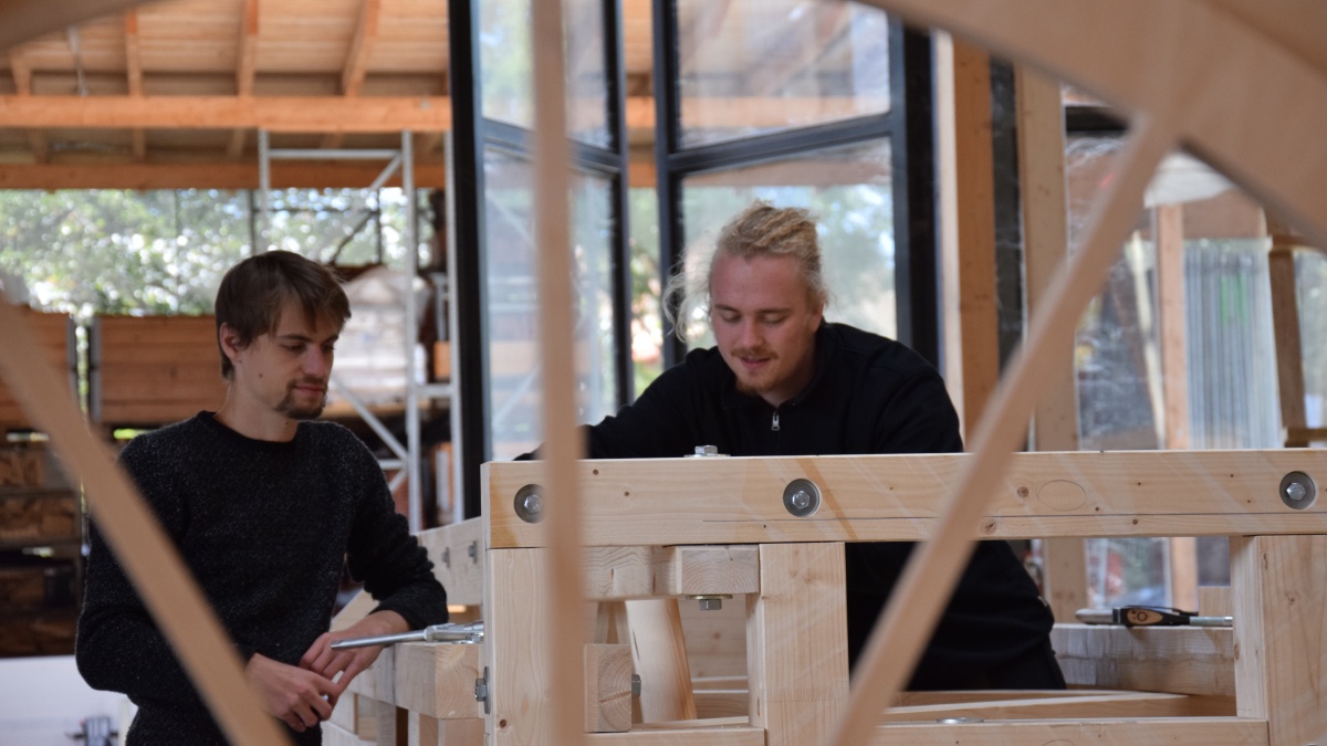 Zwei Studenten bauen am Holzkorpus der Luftbahn
