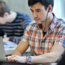Ein Student mit kariertem Hemd arbeitet am Laptop. Foto:
