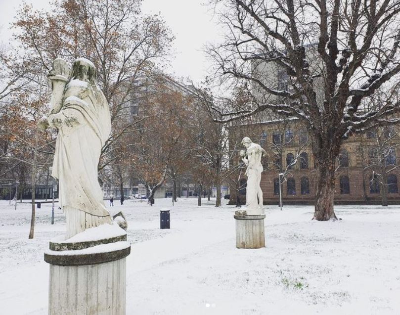 Snowy meadows and statues in Stuttgart city garden.