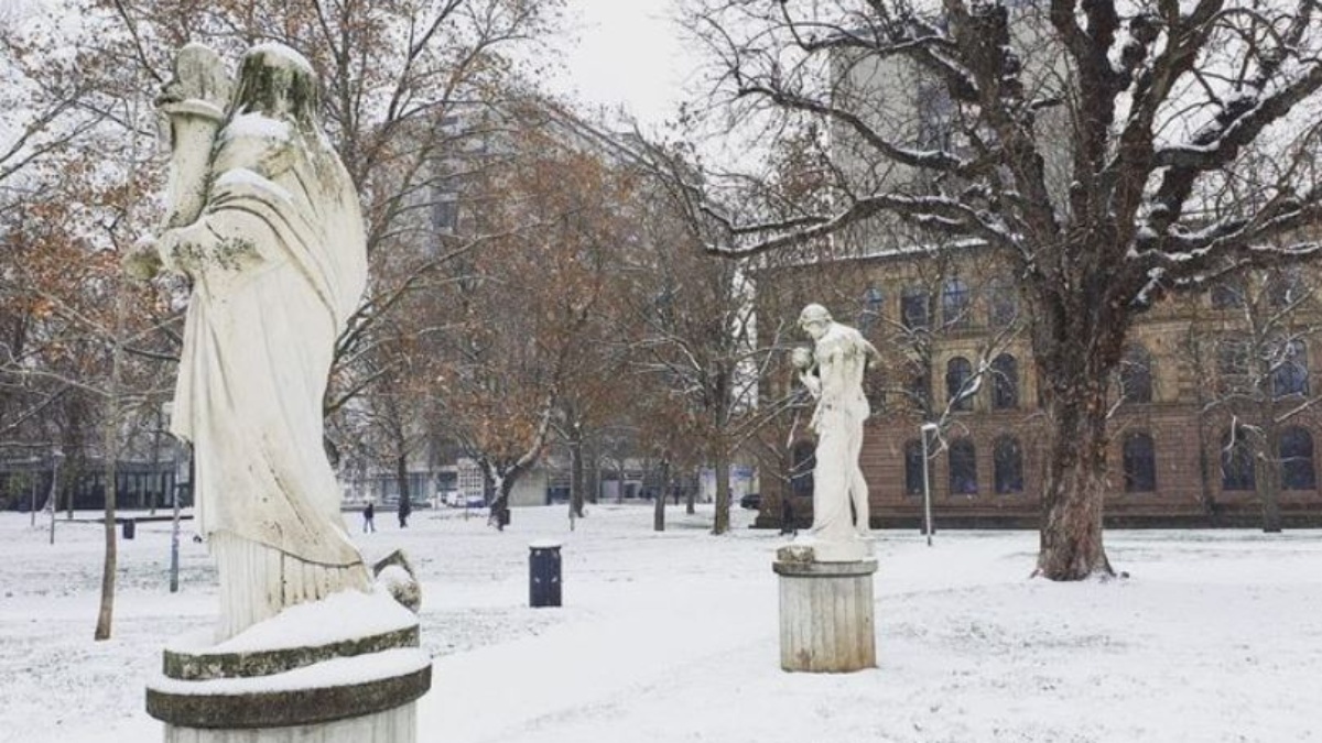 Snowy meadows and statues in Stuttgart city garden.