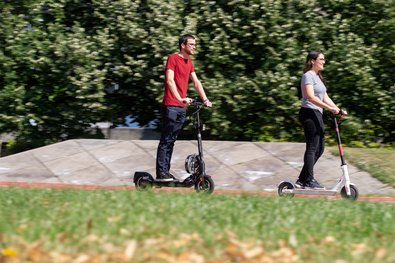 A man and a woman are driving on E-scooters on the Campus Vaihingen.