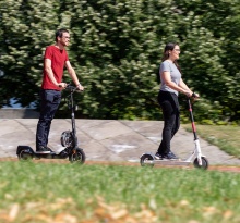 Ein Mann und eine Frau fahren auf E-Scootern über den Campus Vaihingen.