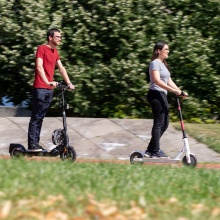 Ein Mann und eine Frau fahren auf E-Scootern über den Campus Vaihingen.