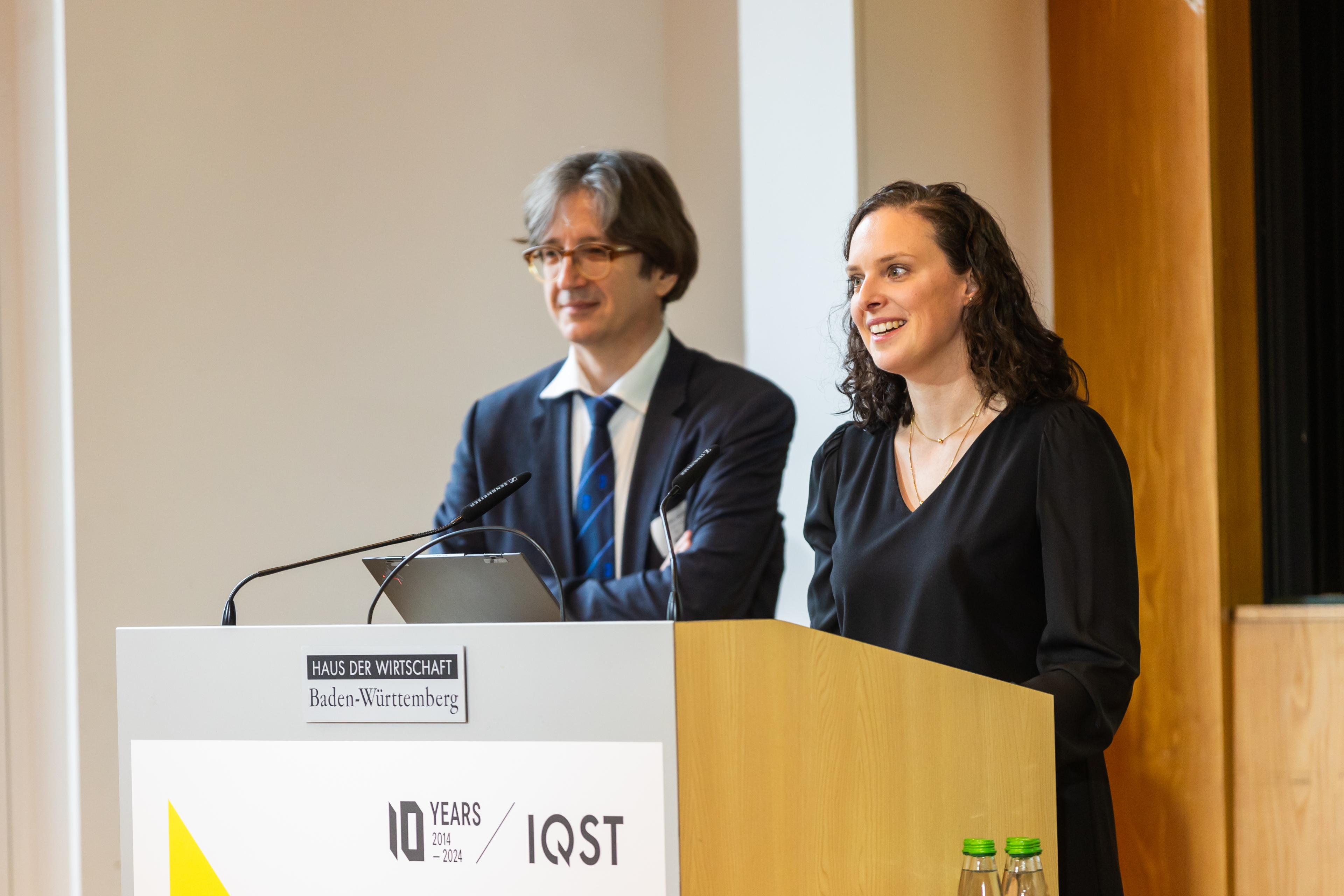 Professorin Stefanie Barz (rechts im Bild) und Professor Fedor Jelezko (links im Bild) von IQST gemeinsam am Rednerpult auf der Bühne. 