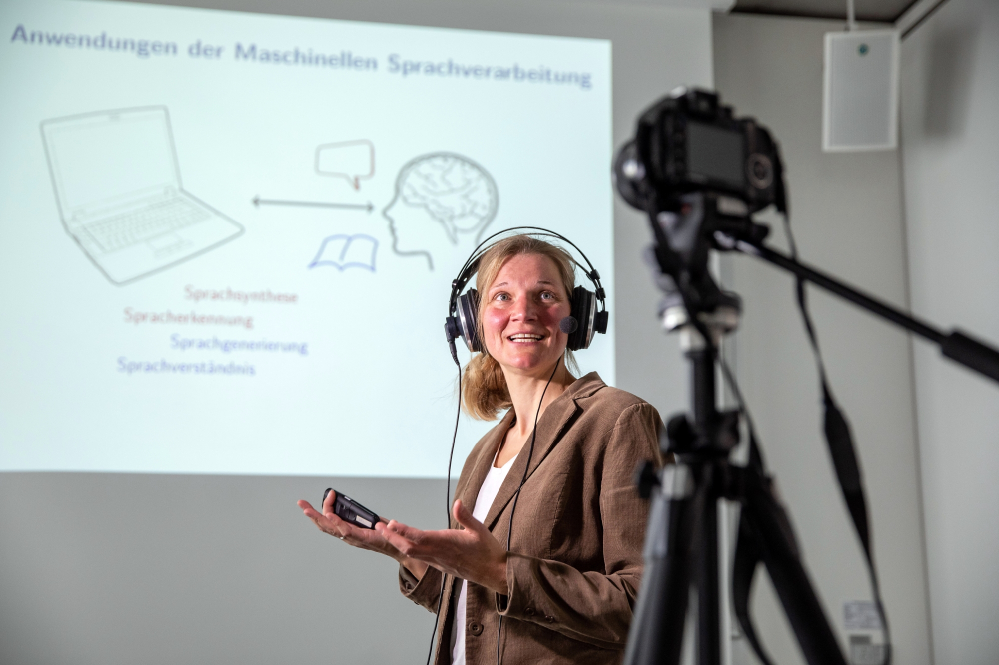 Frau hält eine Lehrveranstaltung und wird dabei von einer Kamera aufgezeichnet.