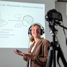 Woman gives a lecture and is recorded by a camera.
