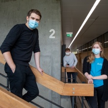 Marius Lichtl und weitere Studierende stehen auf einer Treppe in einem Universitätsgebäude.