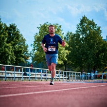 Sportler rennt auf einer Tartanbahn.