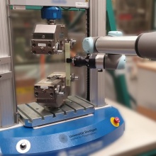 The collaborating robot inserts a material sample into the tensile tester.  Additional pieces of measuring equipment, such as e.g. cameras for carrying out the testing automatically, are integrated into the project.