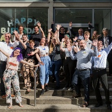 Gruppenfoto des Makerspace-Teams vor dem "Universium". Die Teammitglieder strecken die Arme in die Luft und lachen.
