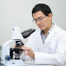 Dr. Tian Qiu at a microscope