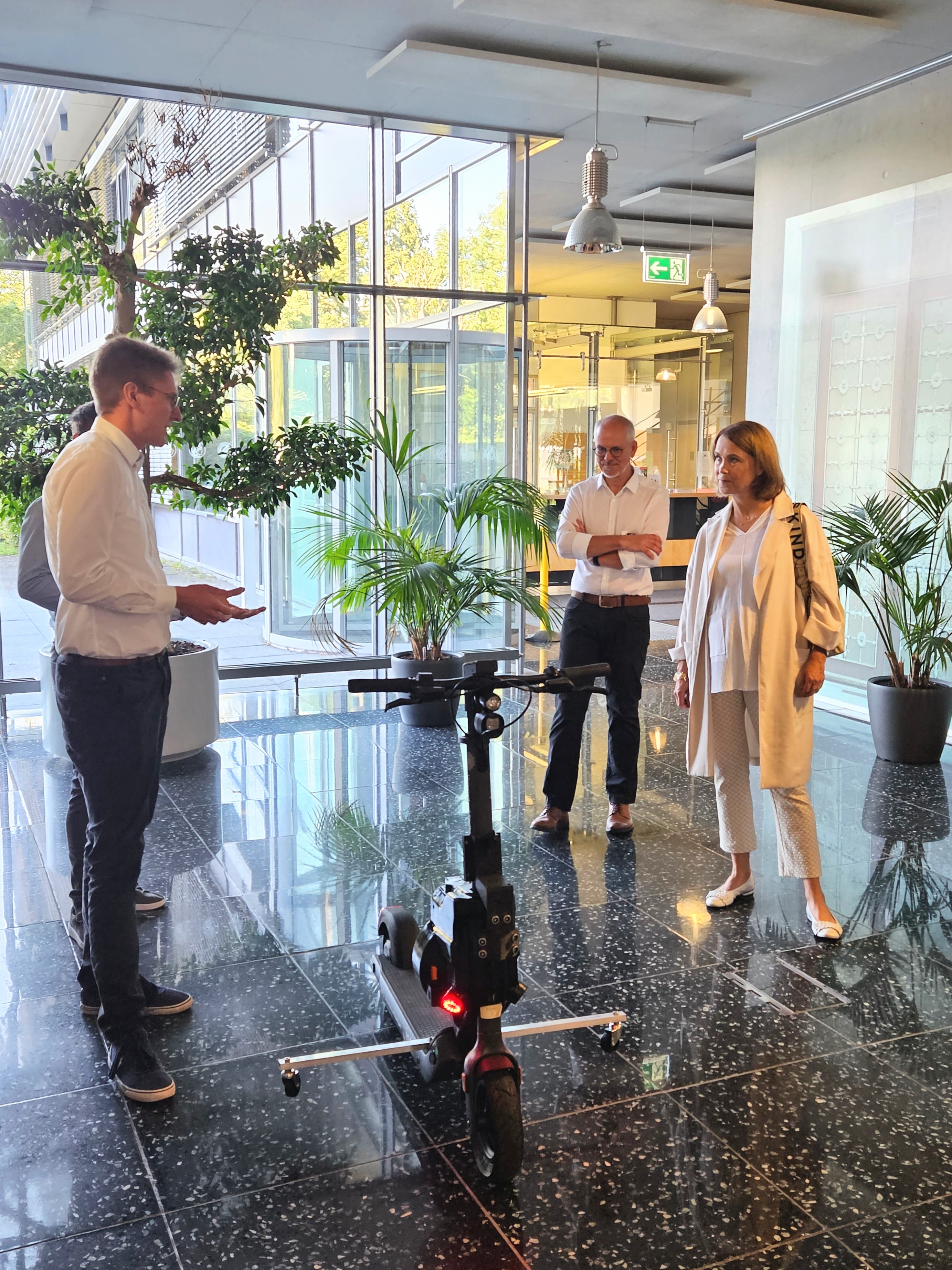 Prof. Allgöwer and an employee present an autonomously driving e-scooter to Minister Olschowski.