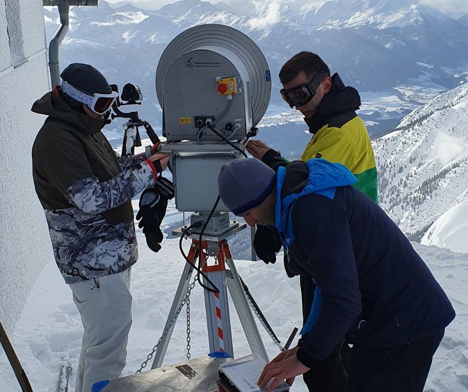 Ein Forscherteam installiert eine Reflektorantenne in den Alpen. 