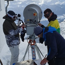 Ein Forscherteam installiert eine Reflektorantenne in den Alpen. 