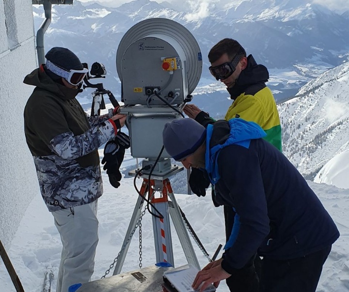 A team of ressearches installing a reflector antenna on a summit in the alps.