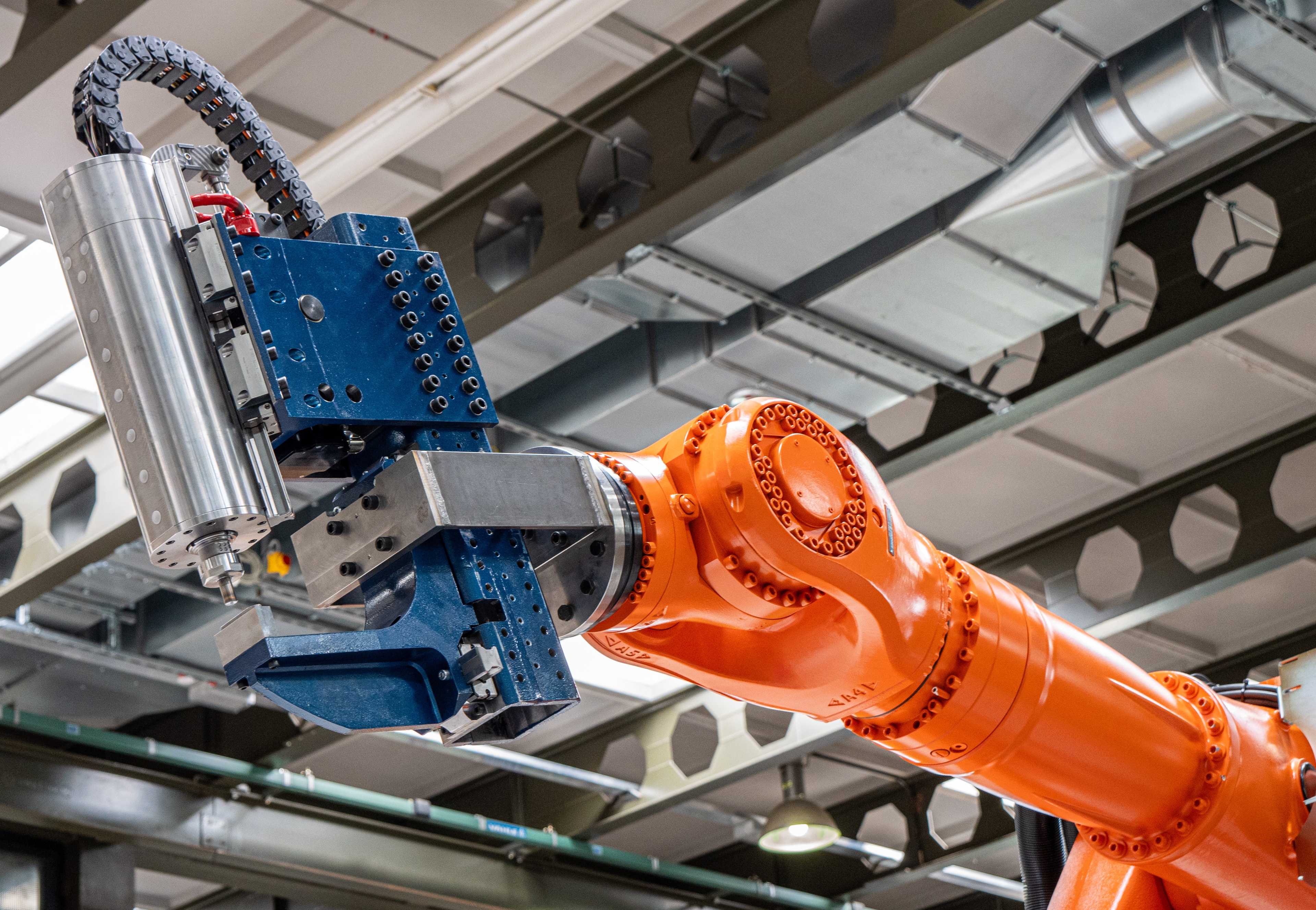 Orangefarbiger Roboterarm mit blau-silberner Schweißzange