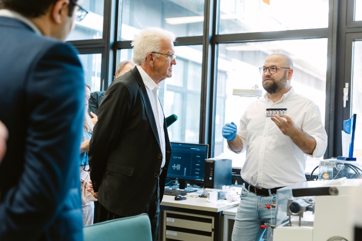 Dr Claudiu Mortan (r.) explains the manufacturing process of perovskites to Prime Minister Kretschmann. The two are in a laboratory at the Institute for Photovoltaics.