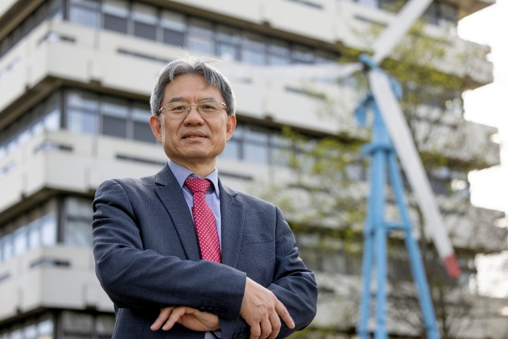 Prof. Yolung Ding stehend vor eine Gebäude