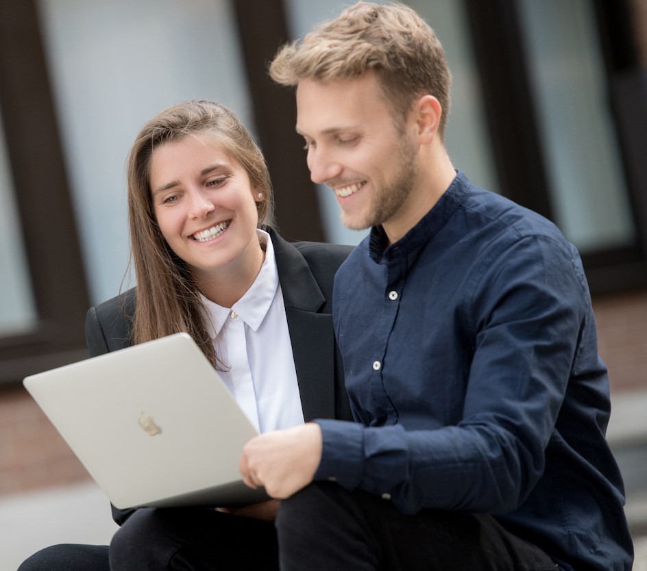 Katharina Hochmuth und Tim Hautkappe sehen zusammen auf einen Laptop.