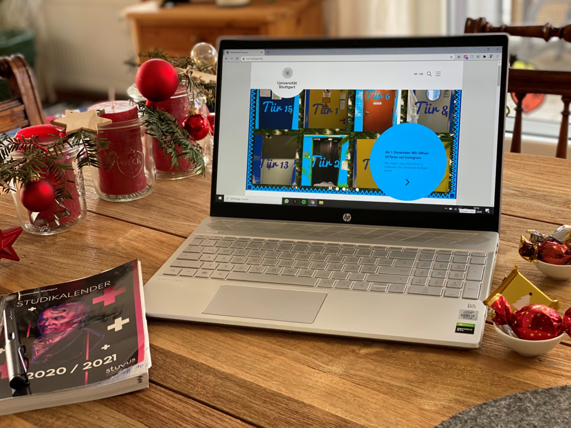 Das Bild zeigt einen Laptop auf einem Tisch. Auf dem Bildschirm ist die Webseite der Universität zu sehen. Der Tisch ist mit Weihnachtsdekoration geschmückt.