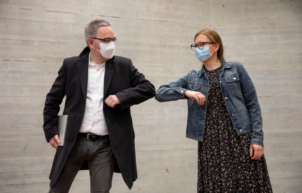 Kanzler Jan Gerken und Anna Haas vom Dezernat 5 tragen beide eine Maske. Sie begrüßen sich mit einem Ellenbogengruß.