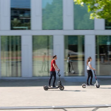 Zwei Personen fahren auf E-Scootern über den Campus der Universität Stuttgart.