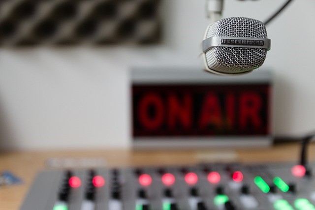 Ein Mikrofon im Vordergrund, im Hintergrund eine Regler-Pult und der Hinweis "On Air"