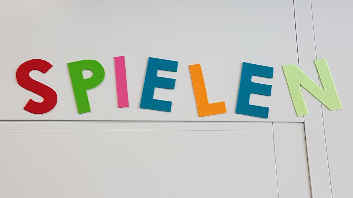 Bunte Buchstaben an der Wand, die das Wort Spielen ergeben.