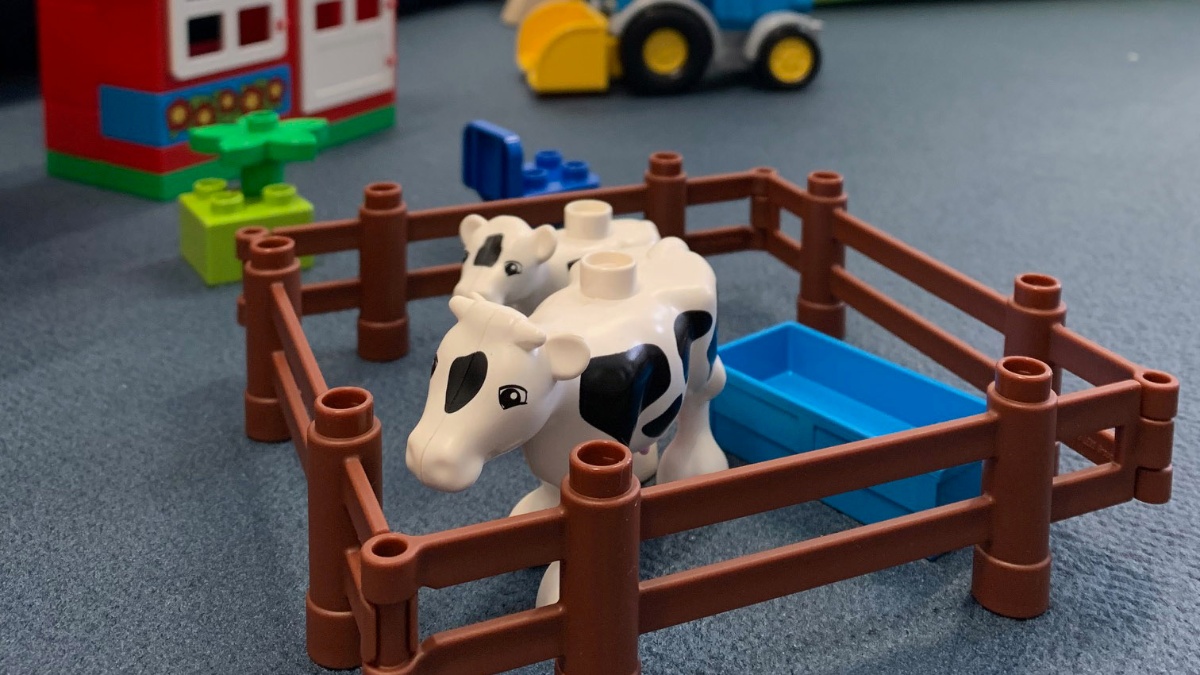 Kindespielzeug mit einer Kuh in einem Zaun auf dem Boden des Eltern-Kind-Zimmers.