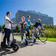 Several people with e-scooters and bicycles on the campus Vaihingen. 