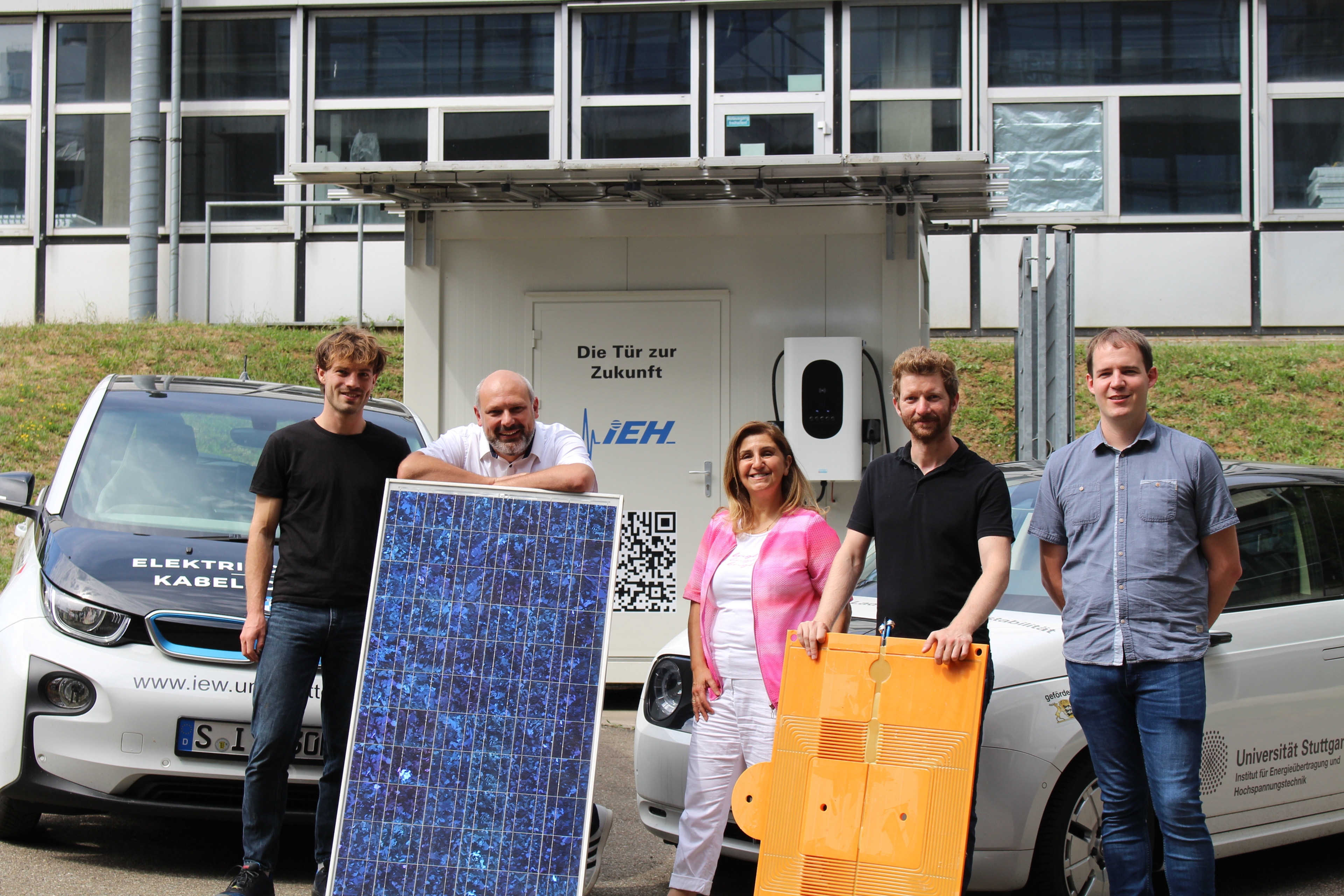 Eine Photovoltaikanlage zur Erforschung induktiver Ladung wird von fünf Personen gezeigt