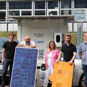 Eine Photovoltaikanlage zur Erforschung induktiver Ladung wird von fünf Personen gezeigt