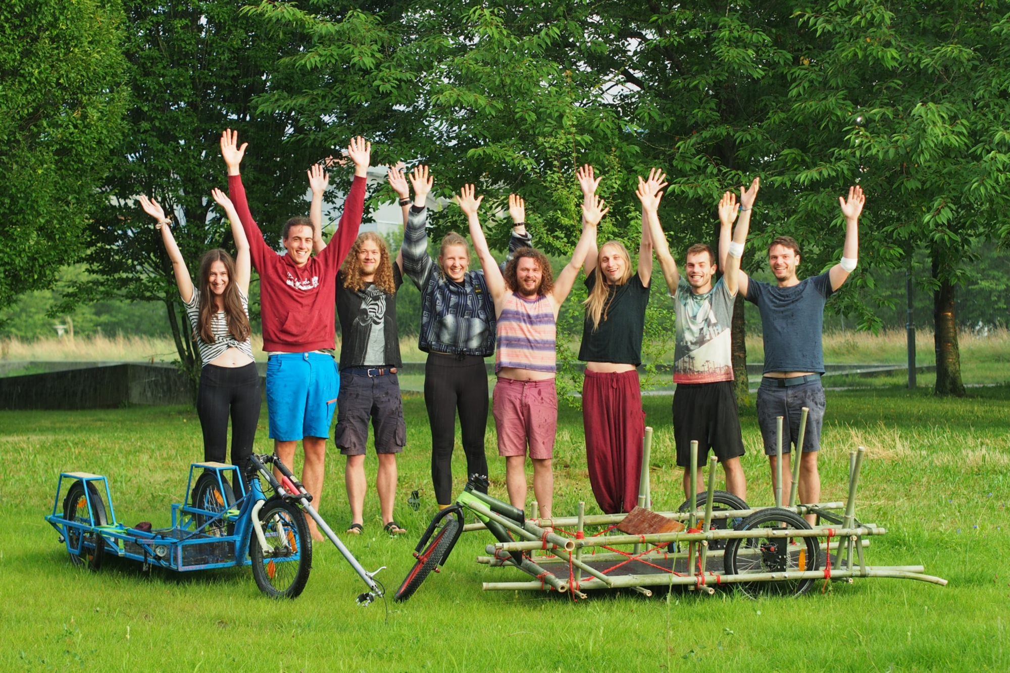 Das Projektteam: acht Studierende, die ihre Arme nach oben strecken und die hinter zwei Lastenrädern stehen.
