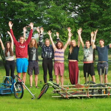 The project team: eight students stretching their arms upwards and standing behind two cargo bikes.